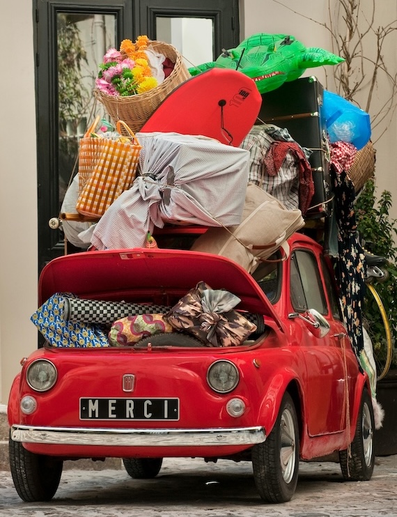 A little red car overloaded by luggage